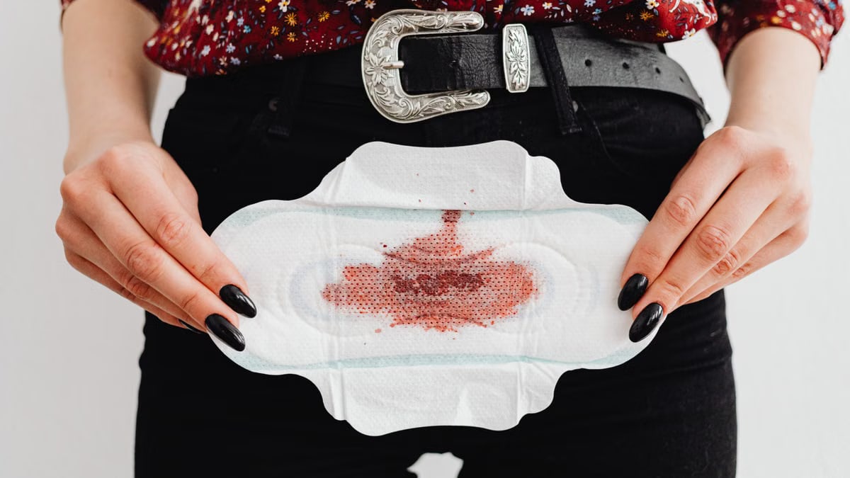 Close-up view of a woman holding a stained menstrual pad, emphasizing menstruation awareness.
